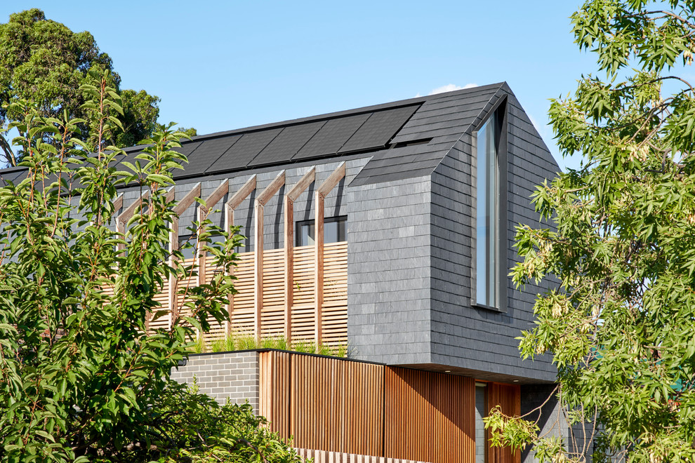 Идея дизайна: деревянный, черный частный загородный дом в современном стиле с двускатной крышей и крышей из гибкой черепицы