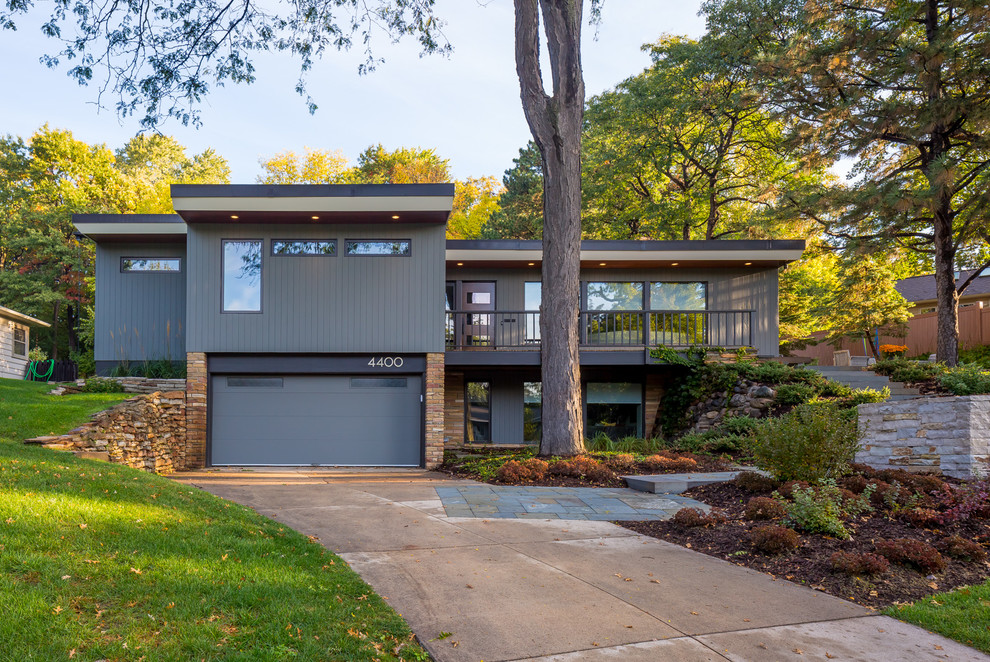 Cette image montre une grande façade de maison grise minimaliste en bois à un étage avec un toit plat.