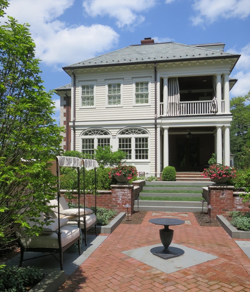Immagine della facciata di una casa ampia bianca classica a due piani con rivestimento in mattoni e tetto a padiglione
