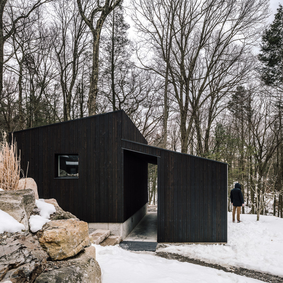 This is an example of a small and black modern bungalow tiny house in New York with wood cladding.
