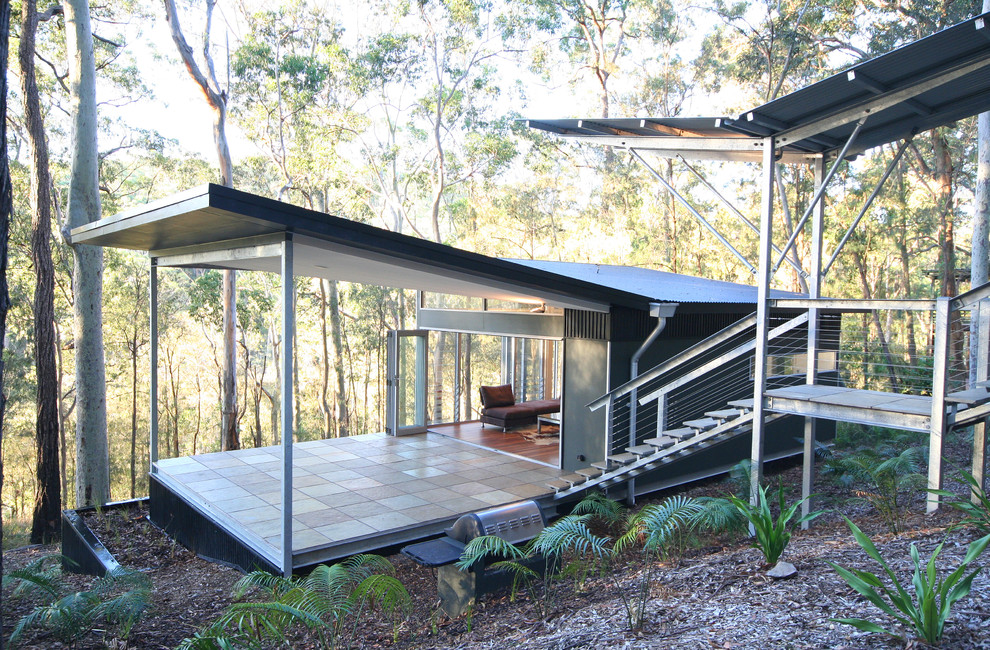 Cette image montre une petite façade de maison métallique et noire design de plain-pied avec un toit plat.