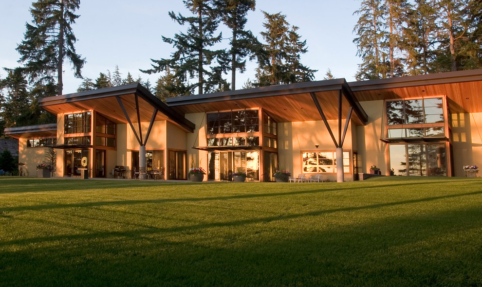 Diseño de fachada de casa beige tradicional renovada grande de una planta con revestimiento de estuco y tejado de un solo tendido