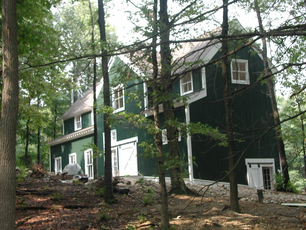 Immagine della villa grande verde country a tre piani con rivestimento in legno, tetto a capanna e copertura a scandole