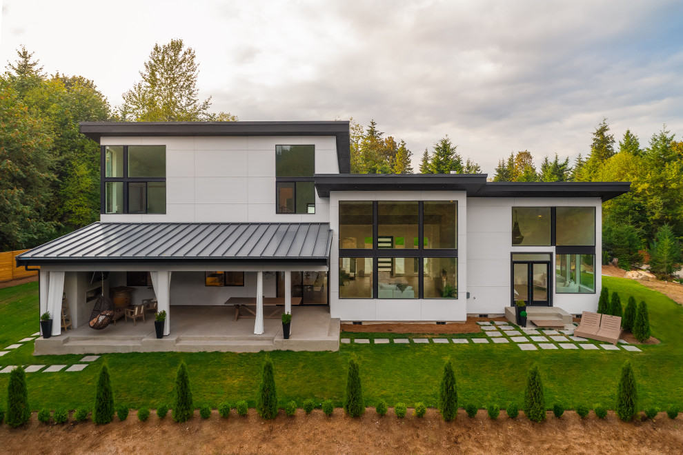 На фото: большой, двухэтажный, белый частный загородный дом в стиле модернизм с комбинированной облицовкой, односкатной крышей и металлической крышей