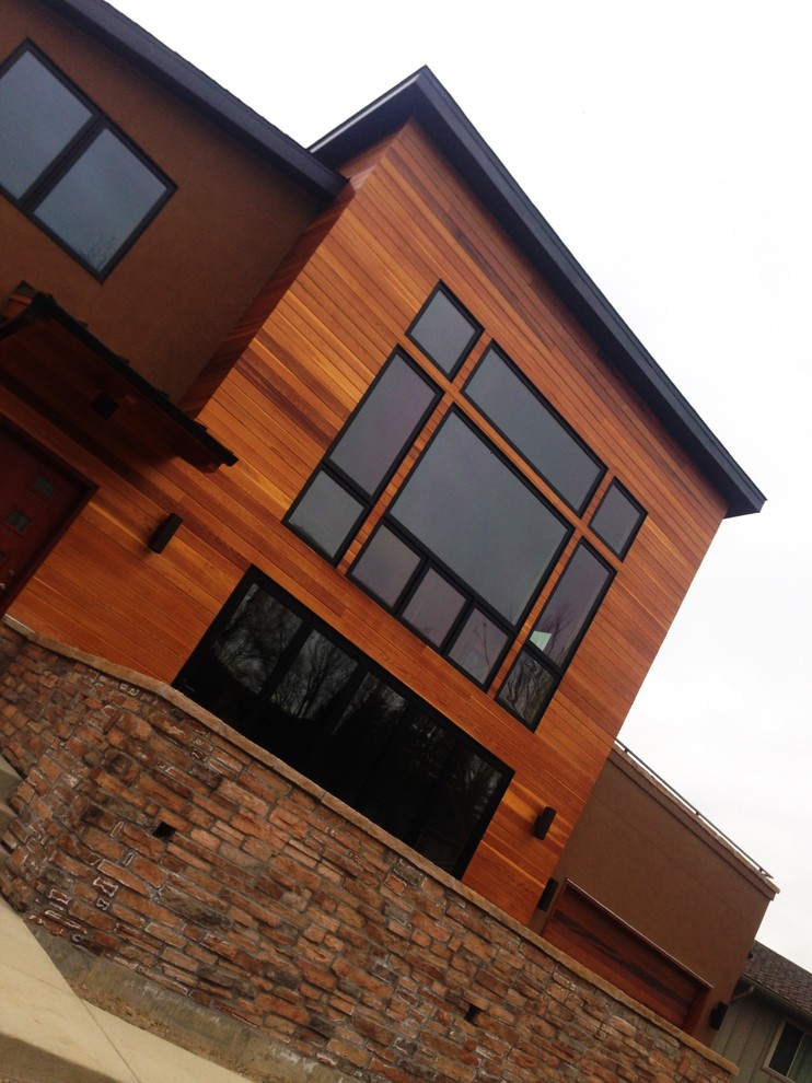 Пример оригинального дизайна: огромный, двухэтажный, коричневый частный загородный дом в стиле неоклассика (современная классика) с комбинированной облицовкой