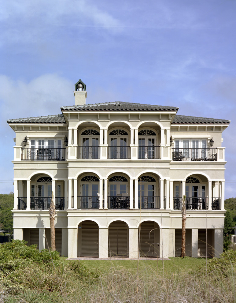Cette image montre une grande façade de maison grise marine en stuc à deux étages et plus avec un toit à deux pans.