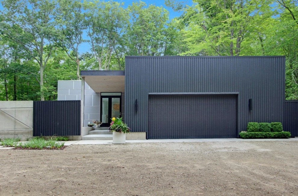 На фото: большой, двухэтажный, черный дом в стиле модернизм с облицовкой из ЦСП и плоской крышей