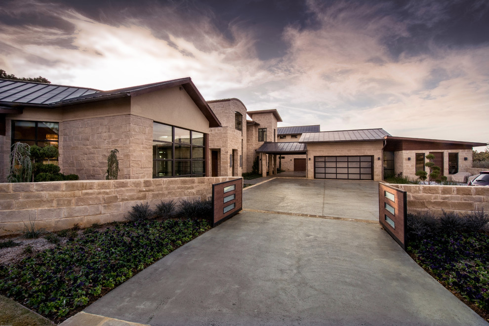Huge contemporary beige two-story stone exterior home idea in Orange County with a metal roof