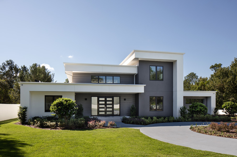 Réalisation d'une très grande façade de maison blanche minimaliste en stuc à un étage avec un toit plat et un toit végétal.