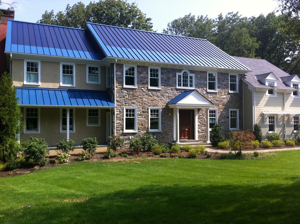 Пример оригинального дизайна: большой, двухэтажный, коричневый дом в классическом стиле с облицовкой из камня, металлической крышей и синей крышей