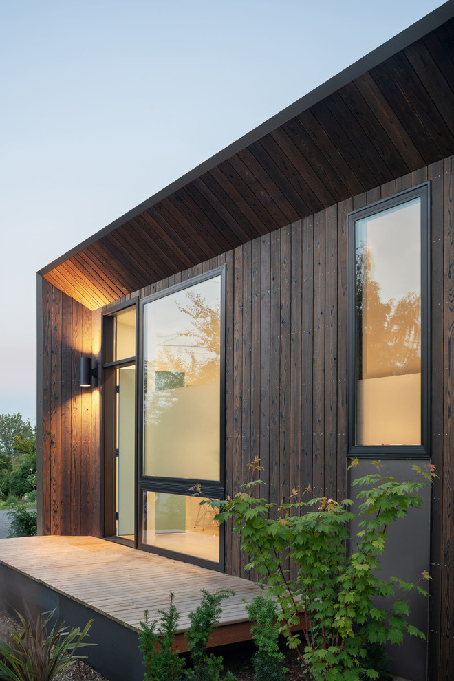 Ejemplo de fachada de piso marrón minimalista pequeña de una planta con revestimiento de madera, tejado plano y tejado de varios materiales
