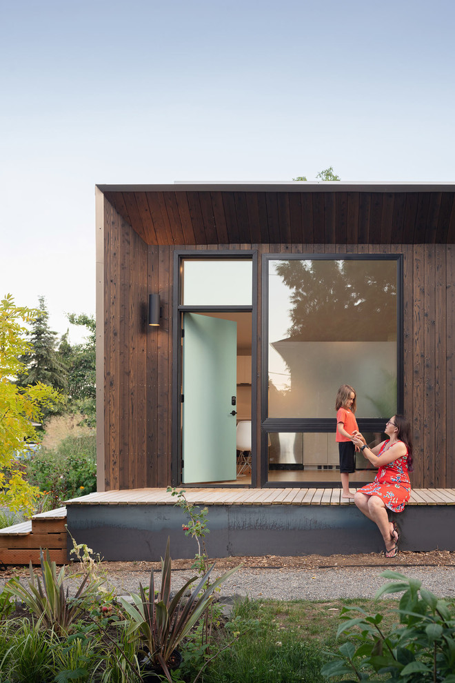 Idee per la facciata di un appartamento piccolo marrone moderno a un piano con rivestimento in legno, tetto piano e copertura mista