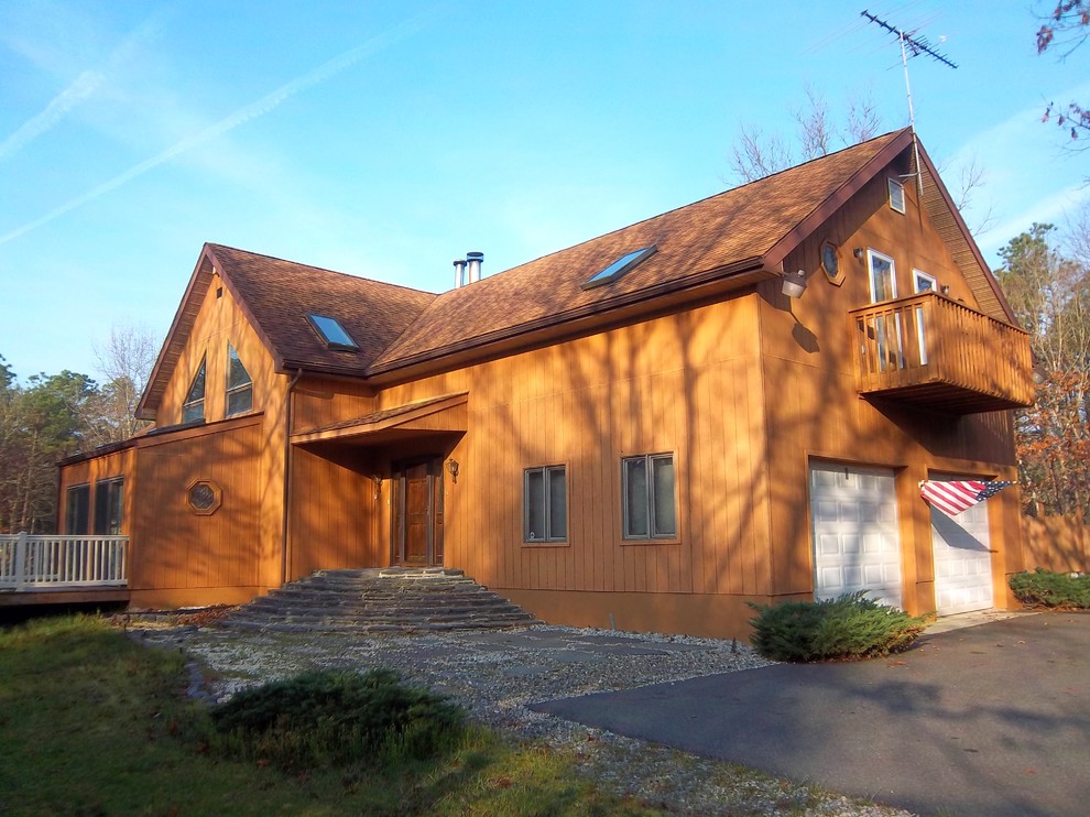Cette image montre une grande façade de maison marron chalet en bois à un étage avec un toit à deux pans.