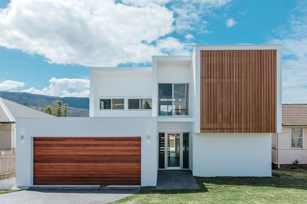 This is an example of a white contemporary two floor detached house in Wollongong with mixed cladding and a flat roof.