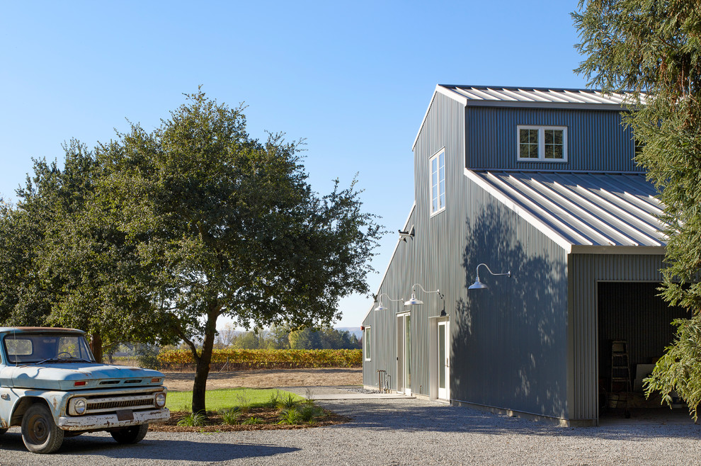Cette image montre une façade de maison métallique et grise rustique à un étage avec un toit à deux pans et un toit en métal.