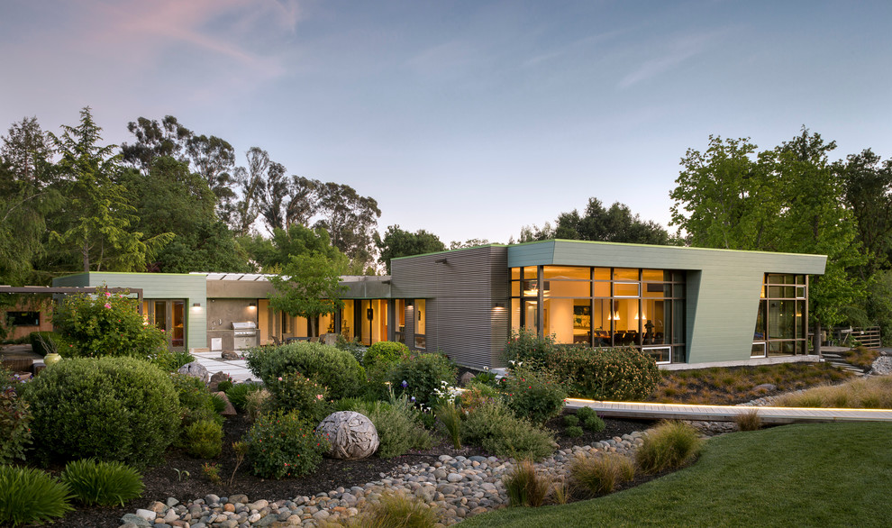 Réalisation d'une façade de maison design de plain-pied avec un revêtement mixte et un toit plat.