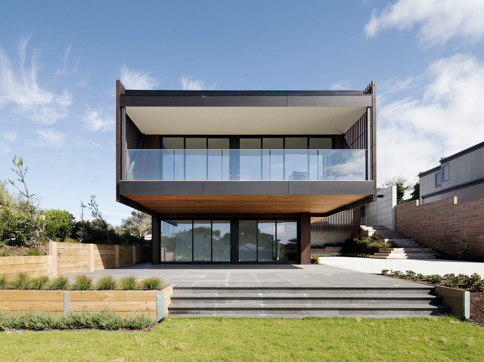 Inspiration för moderna bruna hus, med två våningar, glasfasad och platt tak