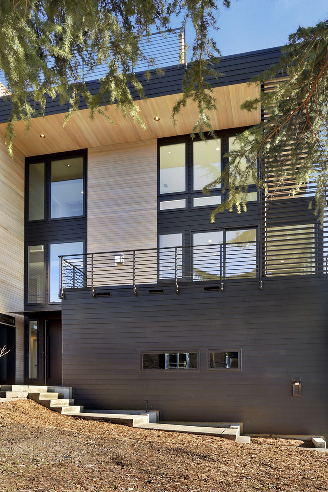 Diseño de fachada de casa negra actual de tamaño medio de tres plantas con revestimiento de aglomerado de cemento y tejado plano