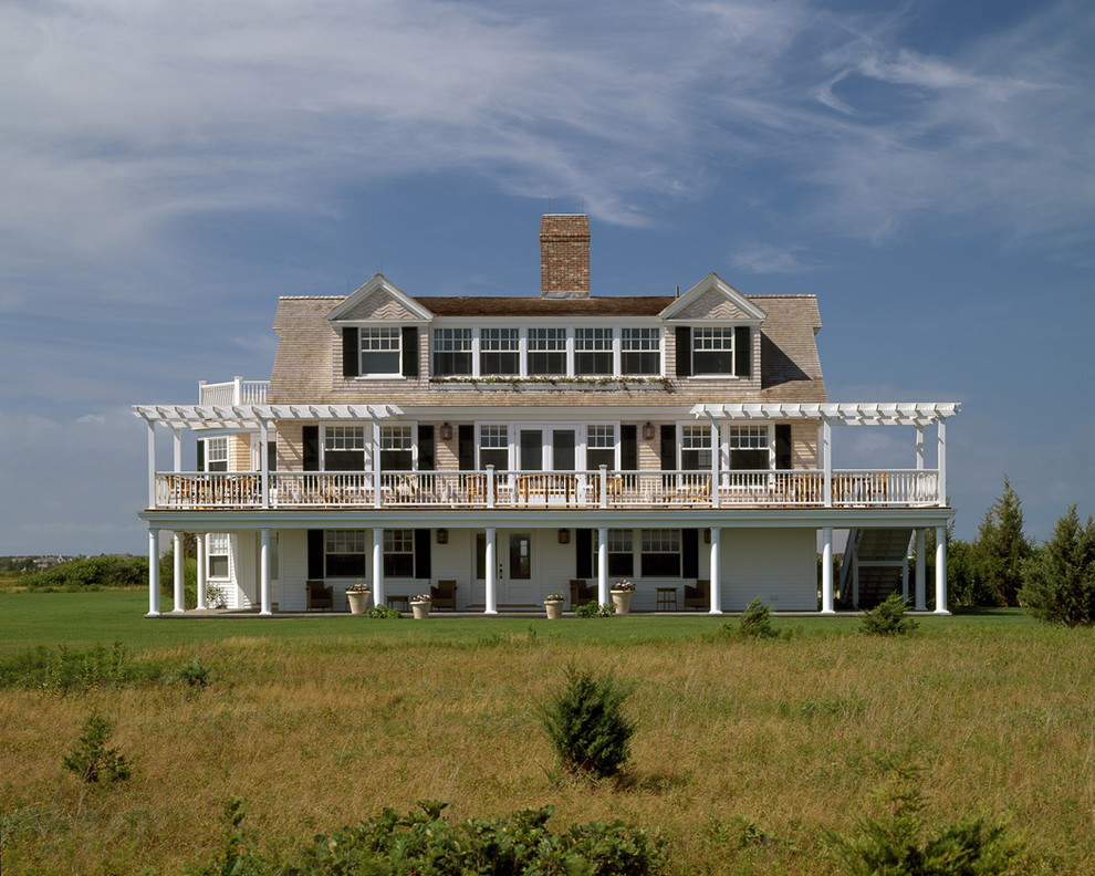 На фото: трехэтажный, деревянный, большой дом в морском стиле с двускатной крышей с