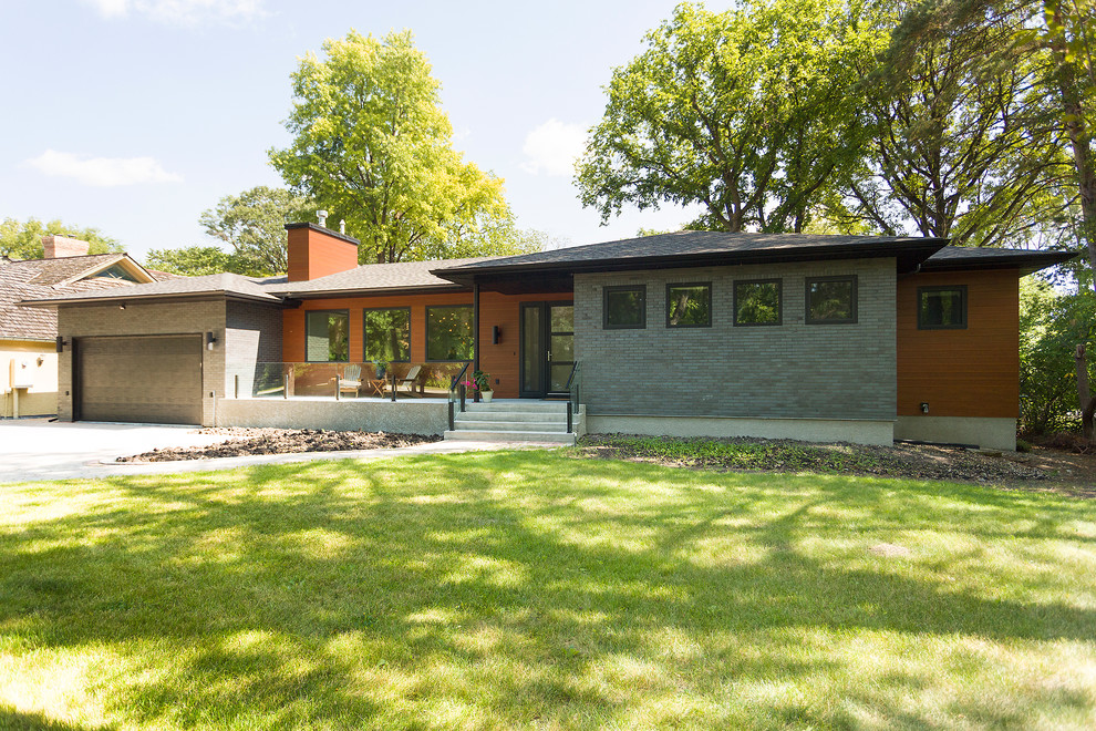 Large mid-century modern multicolored one-story mixed siding house exterior photo in Other with a hip roof and a shingle roof