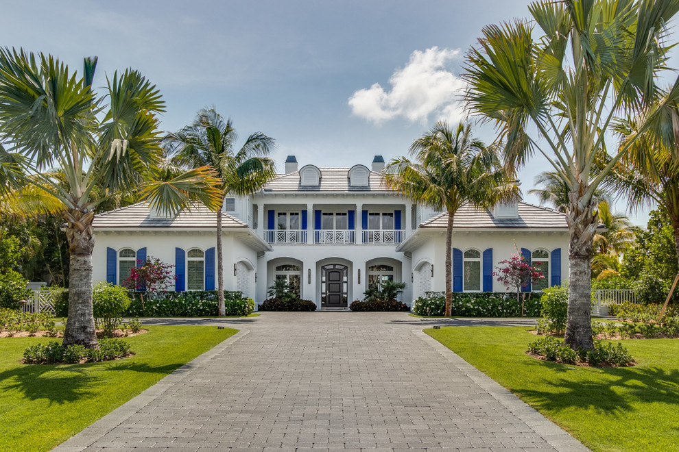 Huge coastal white two-story house exterior idea in Miami with a tile roof