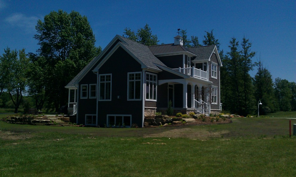 Immagine della facciata di una casa bianca stile marinaro a due piani con rivestimento in vinile e tetto a capanna