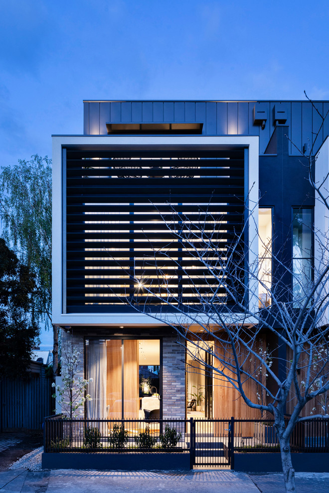 Ispirazione per la facciata di una casa a schiera multicolore moderna a tre piani di medie dimensioni con rivestimento in mattoni, tetto piano, copertura in metallo o lamiera e tetto nero