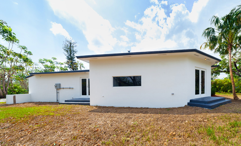 This is an example of a medium sized and white modern bungalow render detached house in Miami with a flat roof.