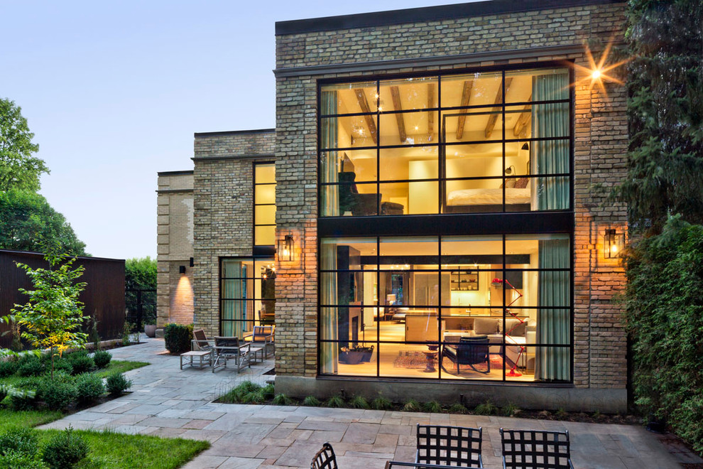This is an example of a large and beige contemporary two floor brick house exterior in Toronto with a flat roof.