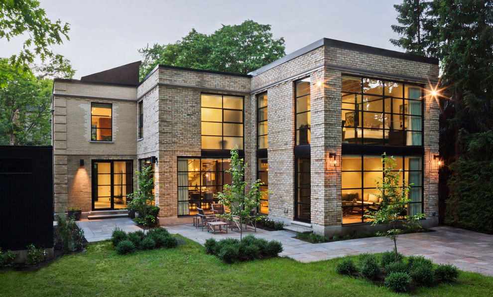 Design ideas for a large and beige contemporary two floor brick house exterior in Toronto with a flat roof.