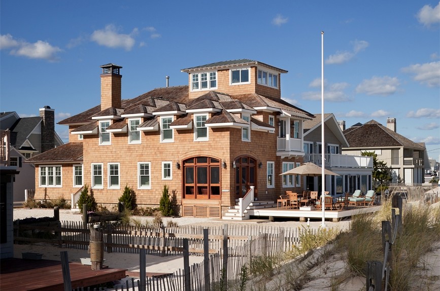 Exemple d'une grande façade de maison marron bord de mer en bois à deux étages et plus avec un toit à quatre pans et un toit en shingle.