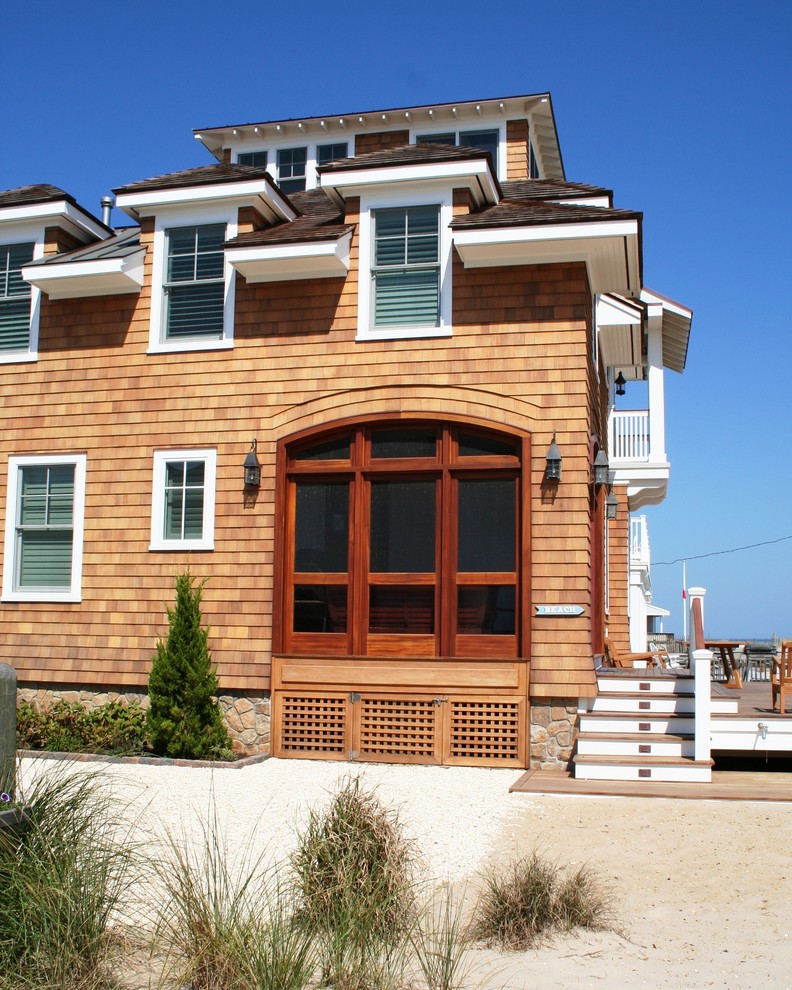 Example of a large beach style brown three-story wood house exterior design in New York with a hip roof and a shingle roof