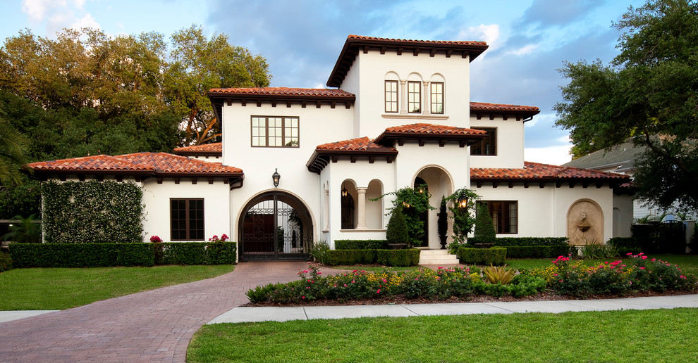 Design ideas for a white mediterranean two floor house exterior in Tampa with a hip roof.
