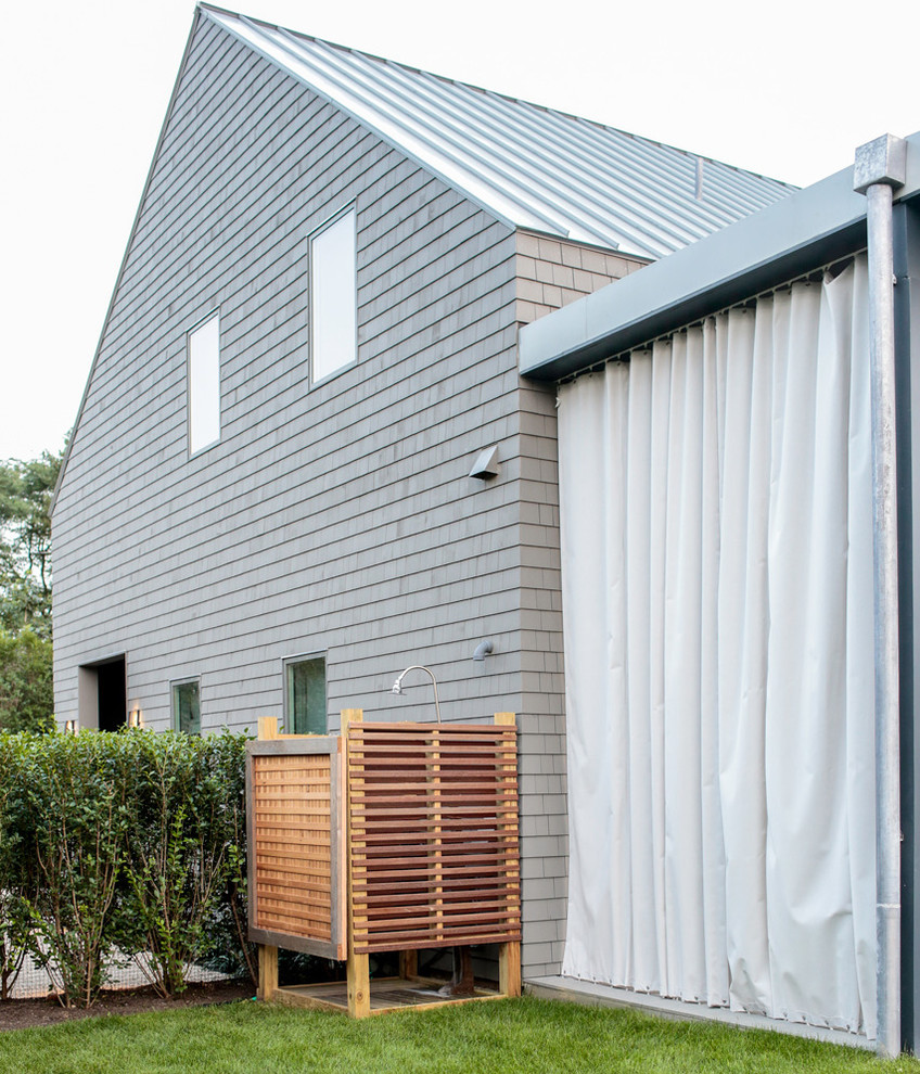 Aménagement d'une façade de maison grise contemporaine en bois de taille moyenne et à un étage avec un toit à croupette et un toit en métal.