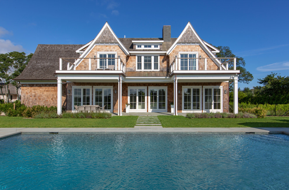 Ejemplo de fachada de casa beige costera de dos plantas con revestimiento de madera y tejado de teja de madera