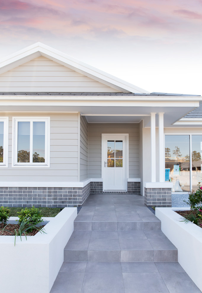 Example of a large beach style gray one-story metal house exterior design in Brisbane with a gambrel roof and a tile roof