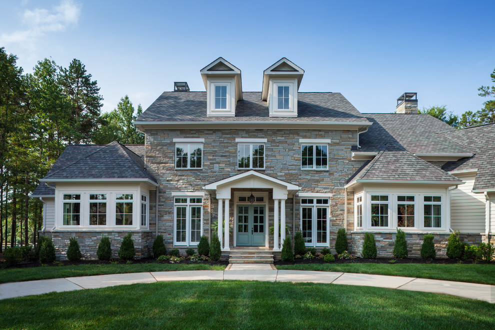 Imagen de fachada de casa blanca clásica renovada grande de dos plantas con revestimiento de piedra, tejado a cuatro aguas y tejado de teja de madera