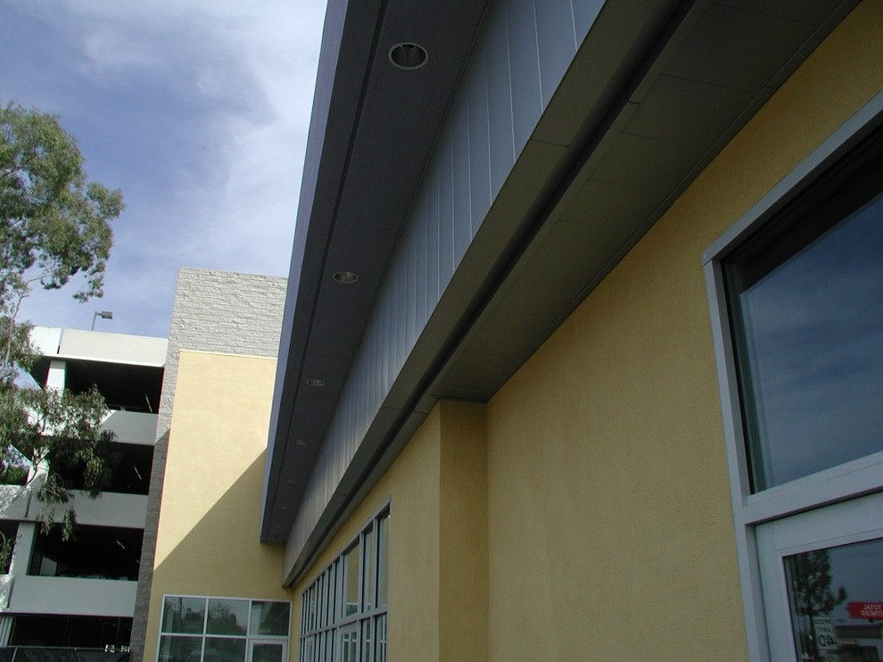 Mid-sized urban yellow one-story stucco flat roof photo in Los Angeles