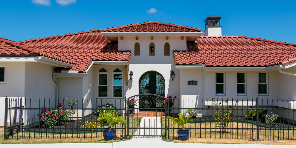 Large tuscan white two-story stucco house exterior photo in Austin with a hip roof and a tile roof