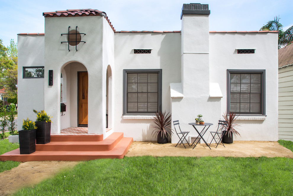This is an example of a large and white mediterranean bungalow render detached house in Los Angeles with a hip roof and a tiled roof.
