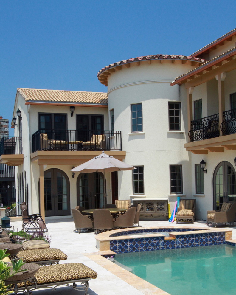 Diseño de fachada beige mediterránea grande de tres plantas con revestimiento de estuco y tejado a dos aguas