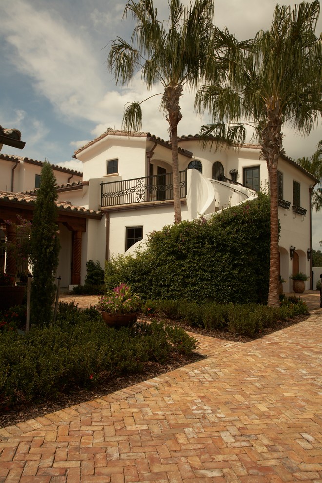 Пример оригинального дизайна: большой, двухэтажный, белый дом в средиземноморском стиле с облицовкой из цементной штукатурки и двускатной крышей