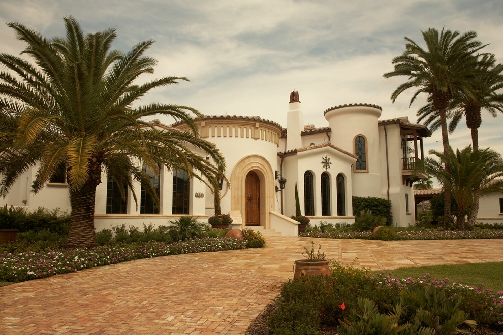 На фото: большой, двухэтажный, белый дом в средиземноморском стиле с облицовкой из цементной штукатурки и двускатной крышей