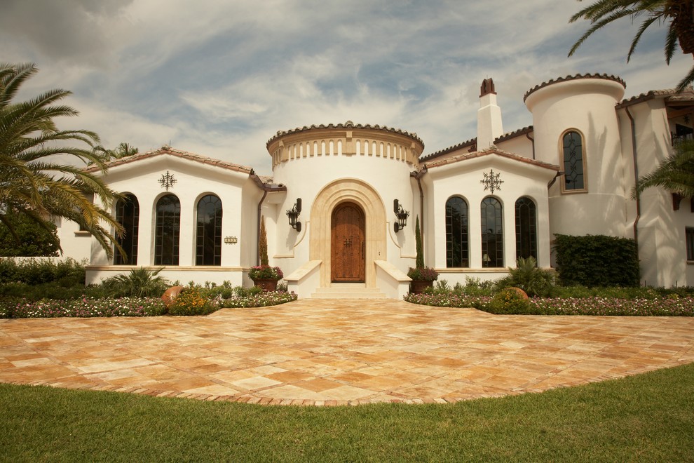 На фото: большой, двухэтажный, белый частный загородный дом в средиземноморском стиле с облицовкой из цементной штукатурки, двускатной крышей и черепичной крышей с
