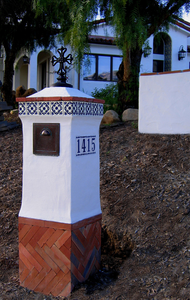 Immagine della villa piccola bianca mediterranea a un piano con rivestimento in stucco, falda a timpano e copertura in tegole