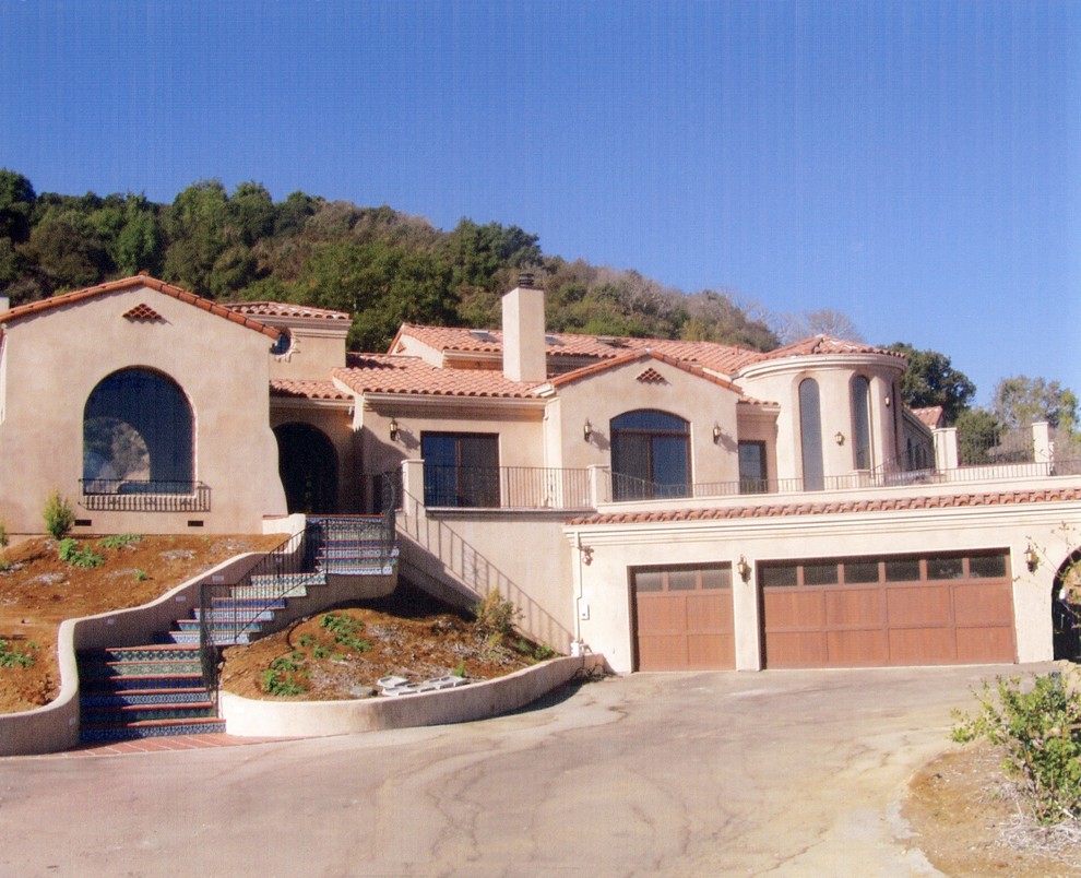 Immagine della villa ampia beige mediterranea a due piani con rivestimento in stucco, tetto a capanna e copertura in tegole