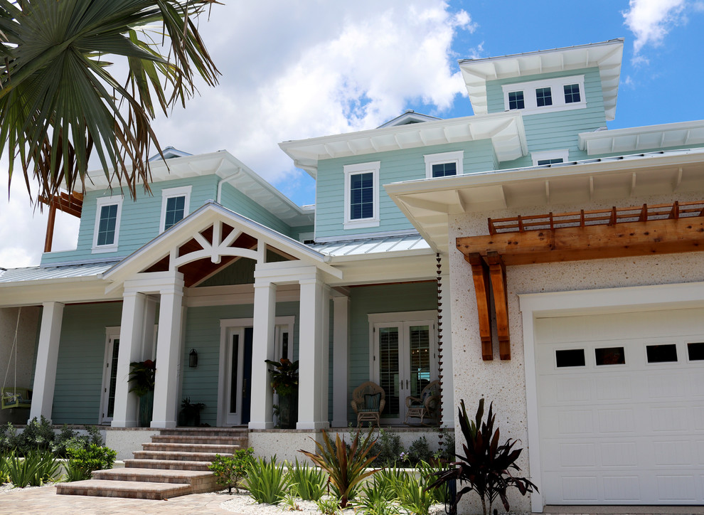 Aménagement d'une façade de maison multicolore bord de mer à un étage avec un revêtement mixte, un toit à quatre pans et un toit en métal.
