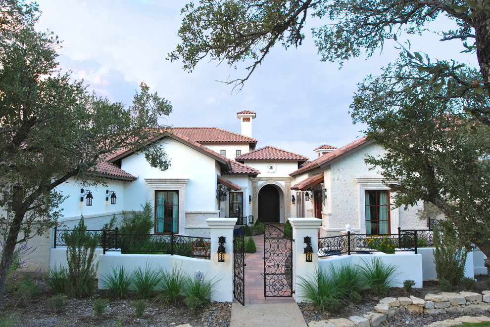 Inspiration for a large mediterranean white stucco house exterior remodel in Austin