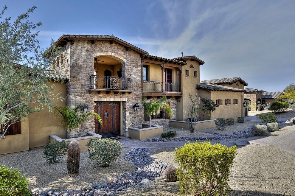 Inspiration for a mediterranean house exterior in Phoenix with stone cladding.