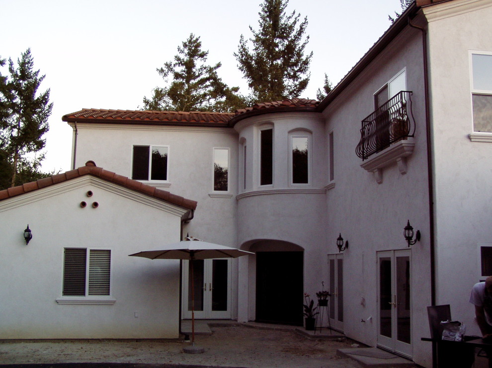 Foto på ett medelhavsstil vitt hus, med två våningar, stuckatur och valmat tak